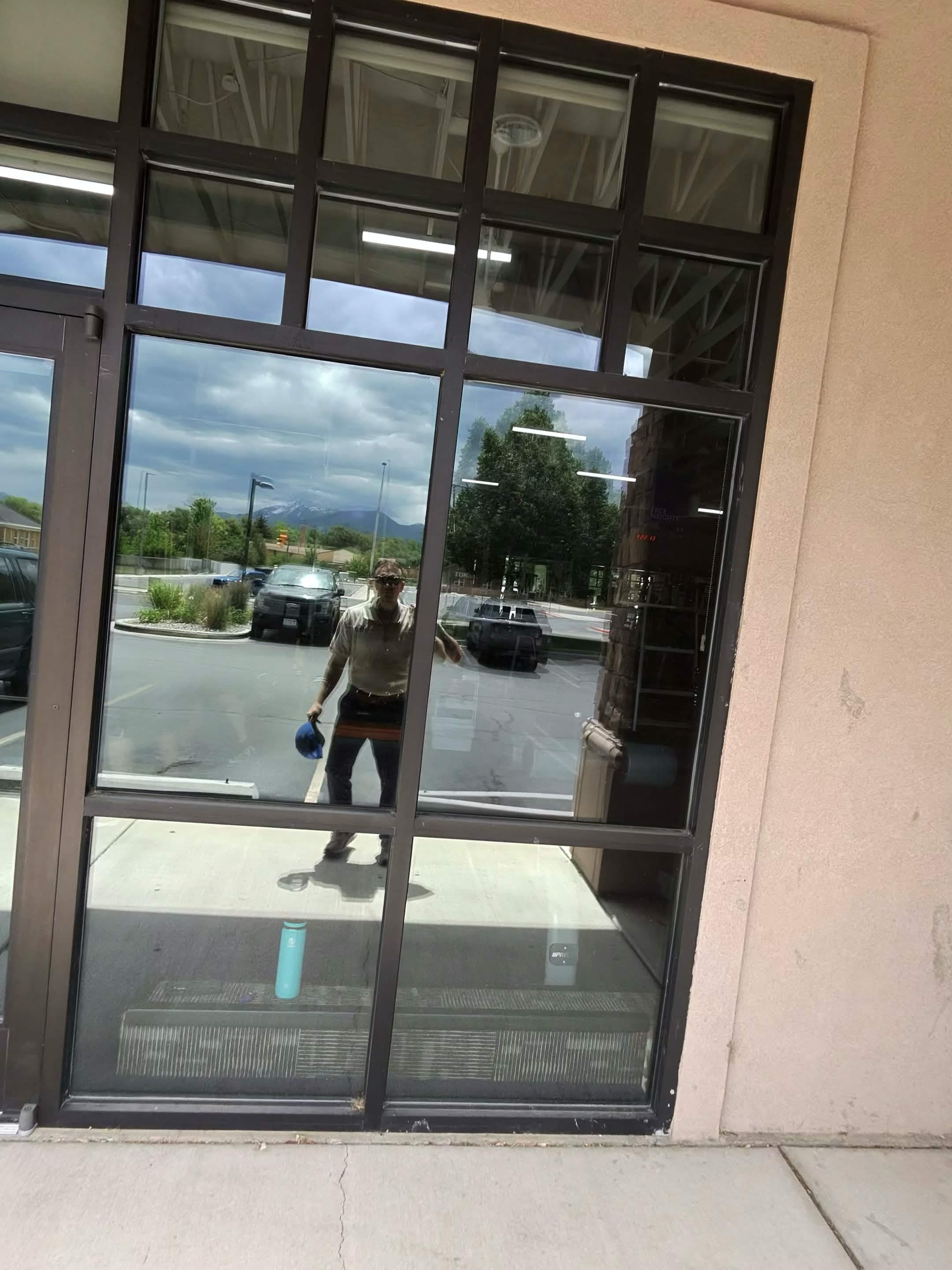 Cleaning the glass storefront of a Utah County business, Mount Nebo in the reflection.
