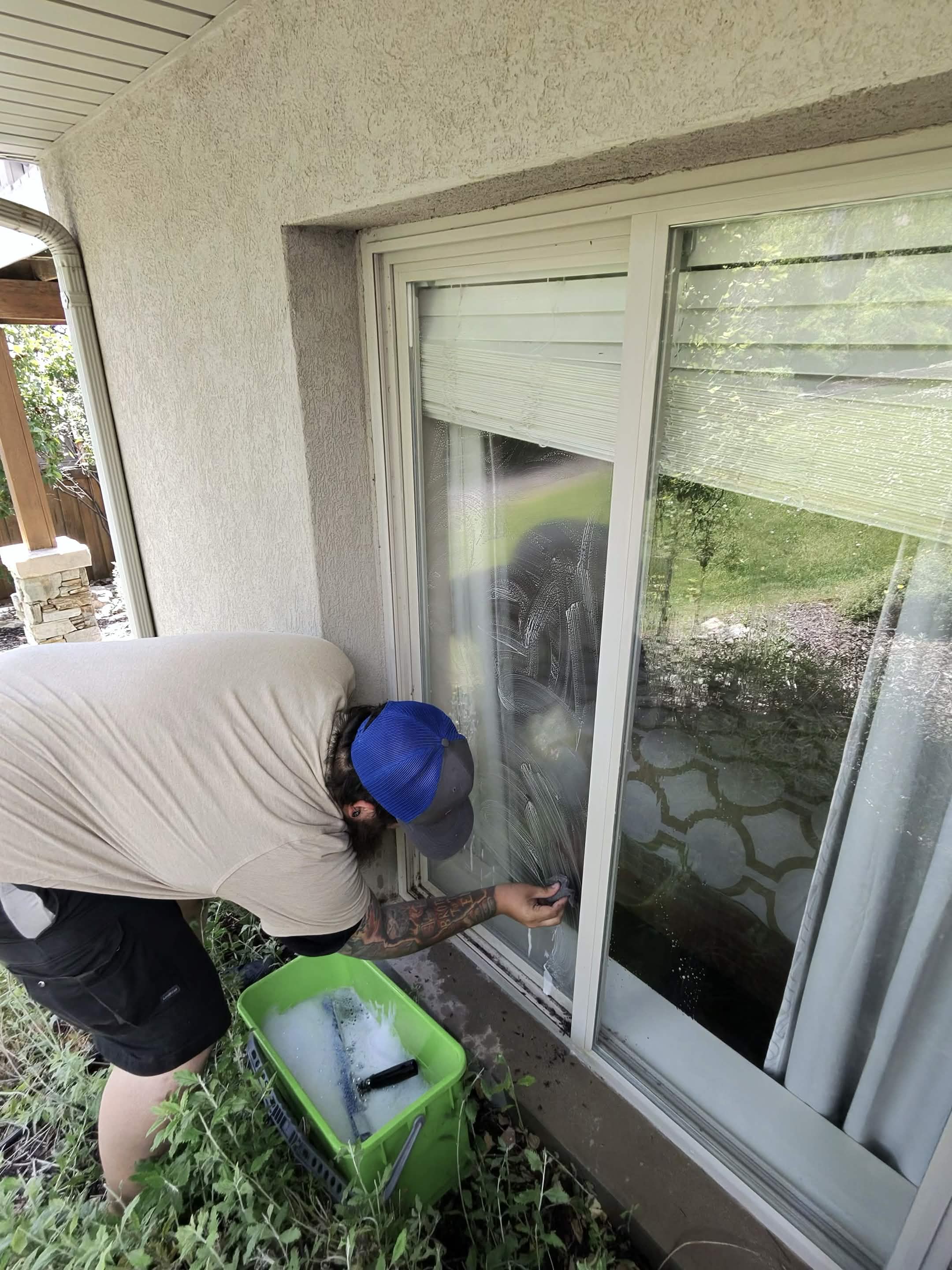 Mountain West technician squeegeeing a large glass door clean at a Utah County home.